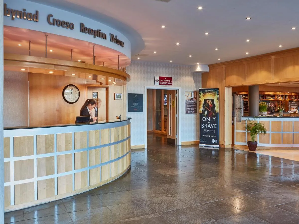 a lobby of a restaurant with a woman standing at a counter at Future Inn Cardiff Bay in Cardiff
