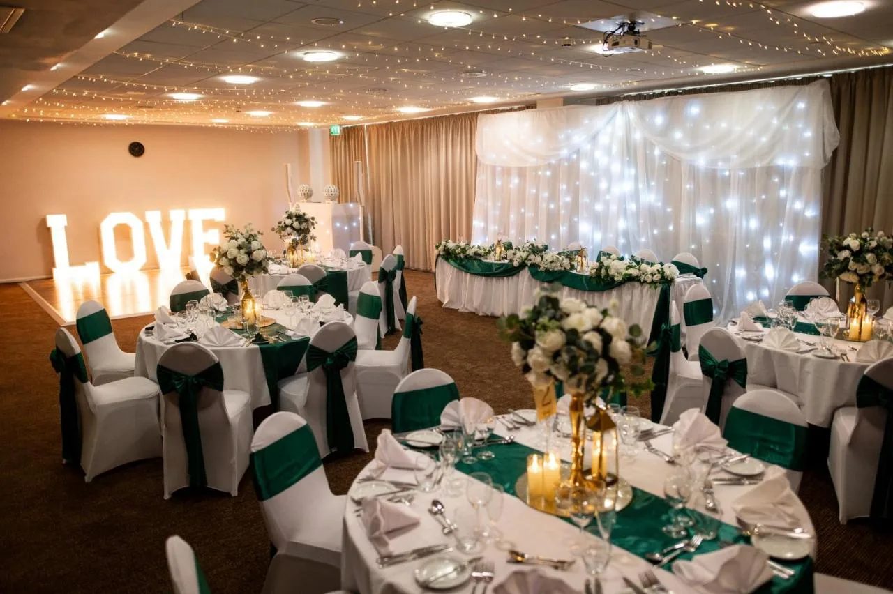 a banquet room with white tables and green chairs at Future Inn Cardiff Bay in Cardiff