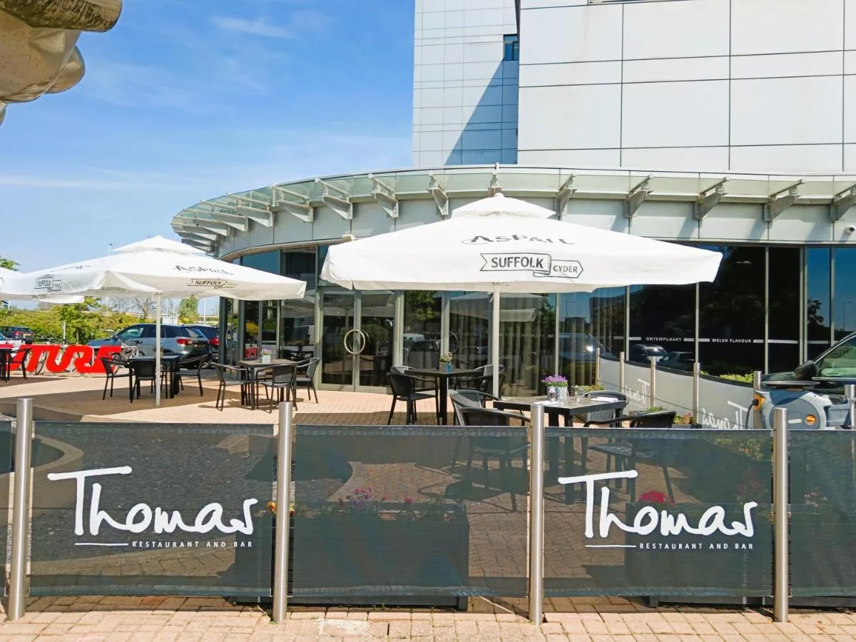 two tables and umbrellas in front of a building at Future Inn Cardiff Bay in Cardiff